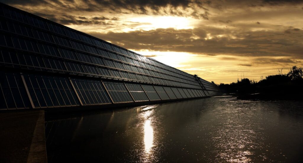 The Art of Drawing Readers In: Your attractive post title goes here Silhouetted solar panels reflect sunset in tranquil waters, showcasing renewable energy.