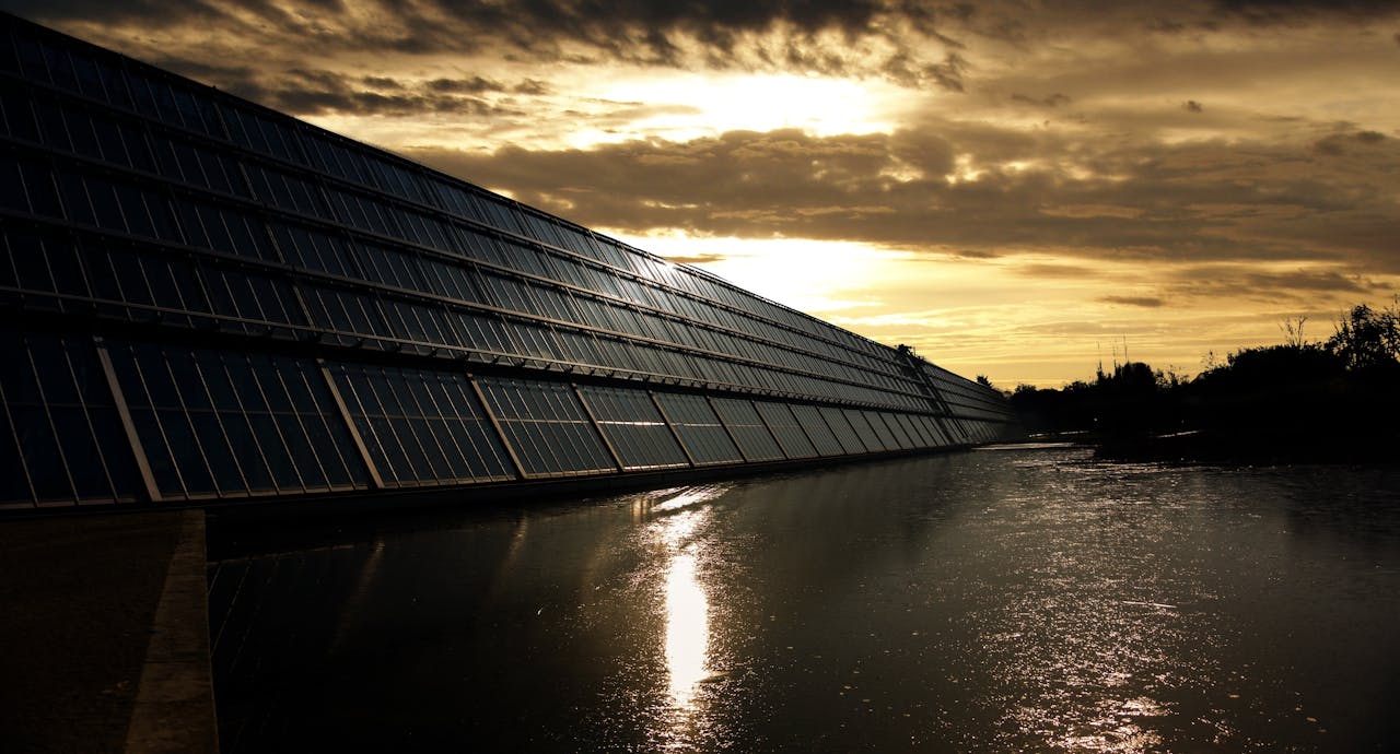 The Art of Drawing Readers In: Your attractive post title goes here Silhouetted solar panels reflect sunset in tranquil waters, showcasing renewable energy.